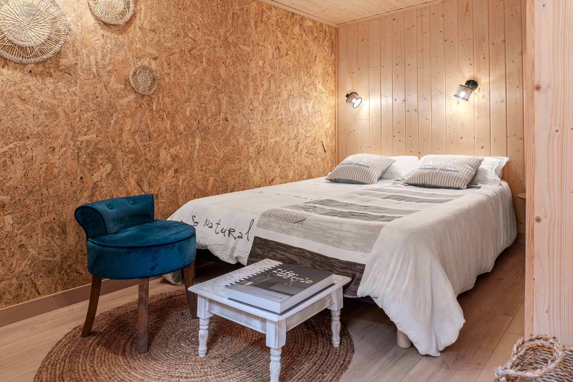 Chambre cosy habillée de bois, fauteuil en velours bleu canard
