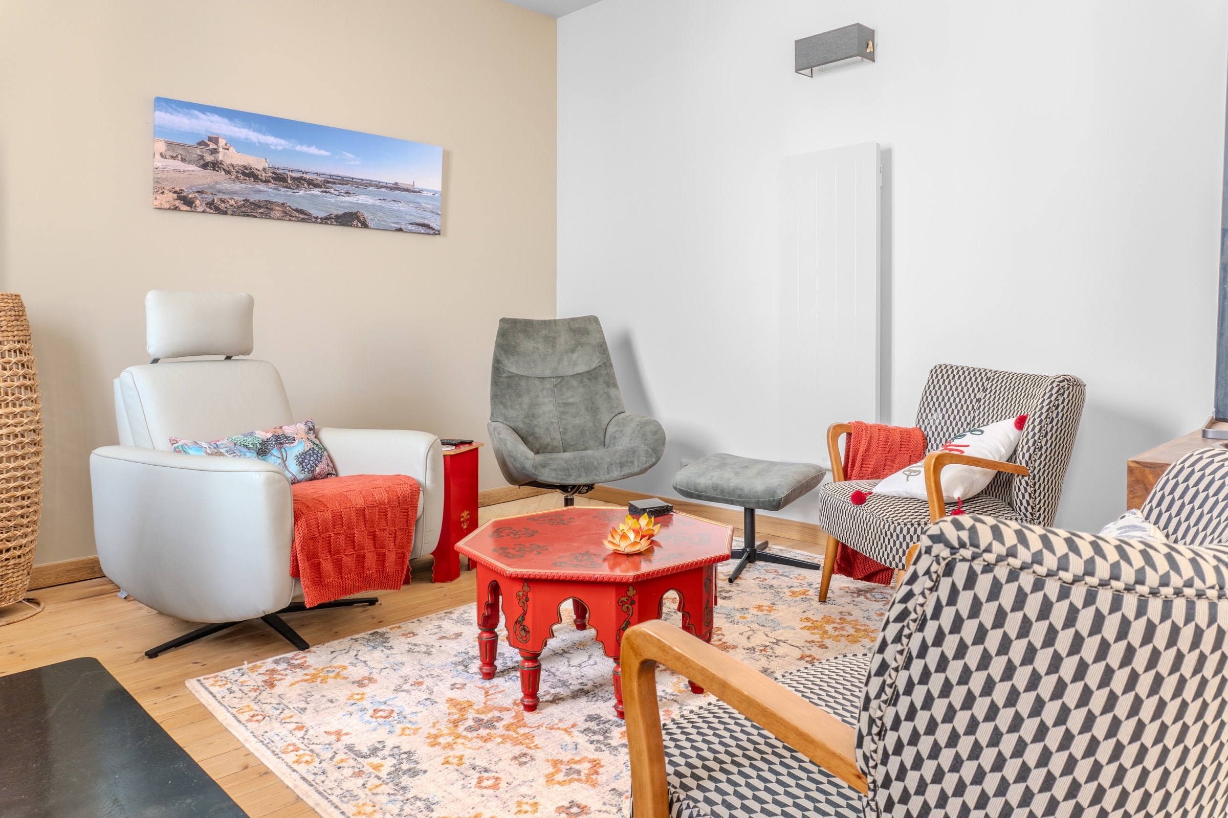 Salon lumineux, fauteuils contemporains et photographie de bord de mer encadrée